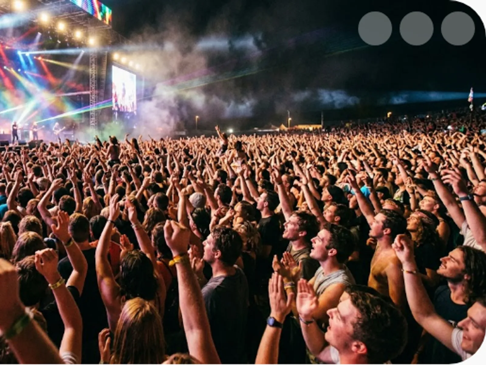 concert crowd with raised hands under colourful stage lights